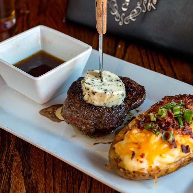 Grilled sirloin steak, with herb garlic butter, peppercorn sauce, and stuffed baked potato.